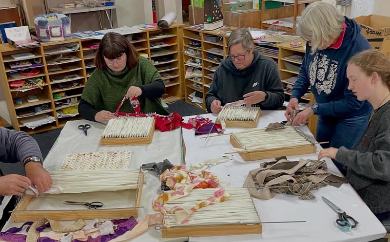 five artists sit around a table making crafts